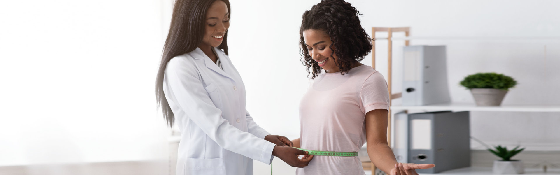 Doctor checking her patient's waistline